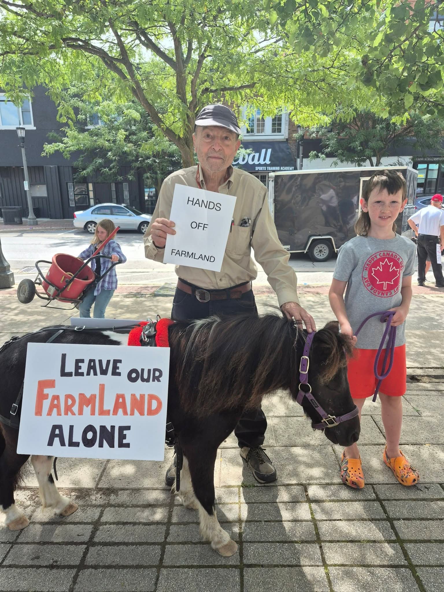 Larry Rosnuk at a farmland protection rally with a child and a pony